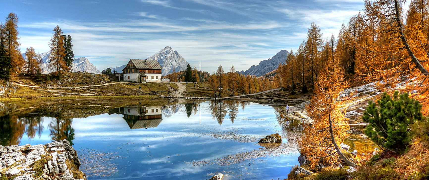 Lago Federa in Italy. An autuminal scene with trees, a lake, mountain and a lone house.