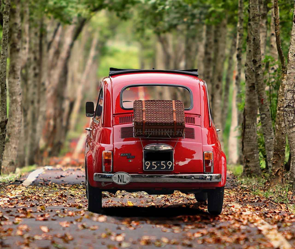 A red Fiat 126 car driving in Autumn on an Italian road
